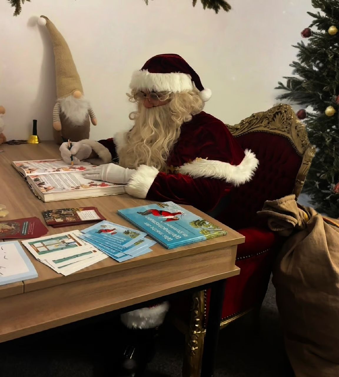 Der Weihnachtsmann sitzt am Schreibtisch und bereitet das Goldene Buch vor